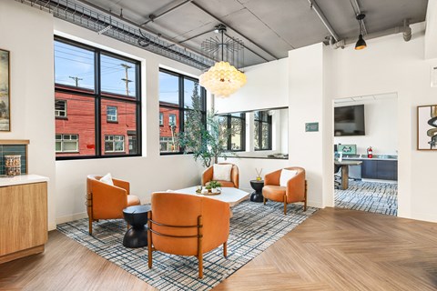 a living room with orange chairs and a table and large windows